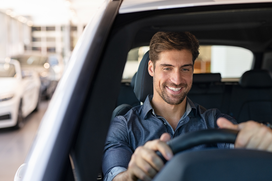 Homem sorrindo ao volante de um carro moderno, transmitindo tranquilidade e satisfação ao dirigir.